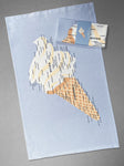 A folded teatowel in a wrap lies on top of an open tea towel, both with the Devon and Cornwall Ice Cream Map design, both sat on a grey background. 