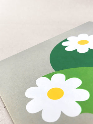 Close up of the Cosmos card detail, showing the precision of white flowers ,golden yellow circle centres and green wide stalks, screenprinted onto grey card.