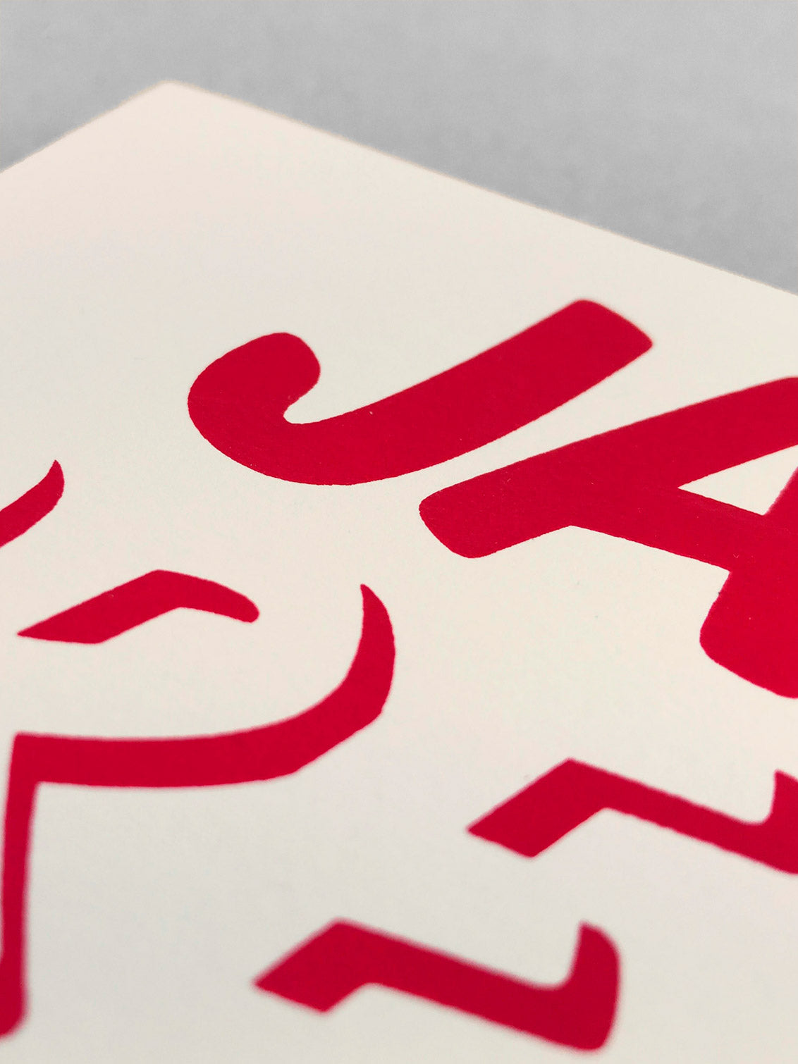 Close up of the cleanly screenprinted red JAM text on cream card.