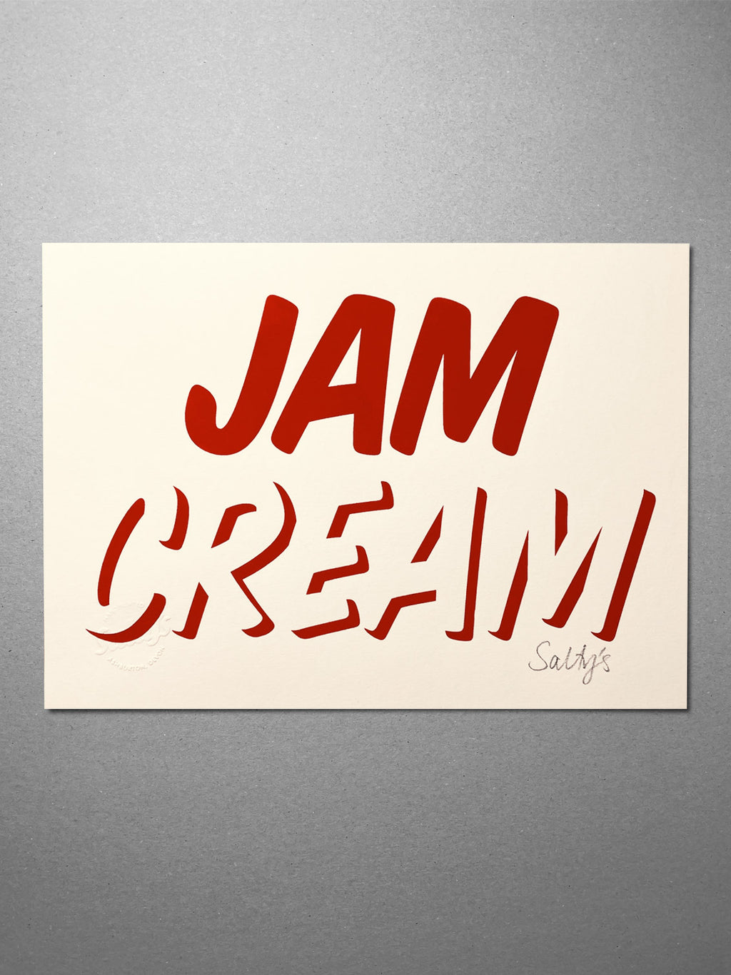 Cleanly printed type in strawberry red ink on a cream coloured recycled card stock, reading CREAM across the bottom with JAM written on top! An A4 print, flat lay from above 